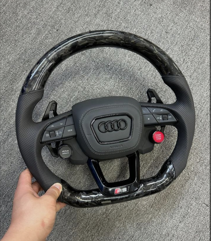 This is a custom carbon fiber flat-bottom steering wheel for an Audi RS3 8Y model. • The wheel features a forged carbon fiber finish on the top and bottom sections, paired with