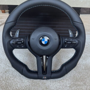 This is a custom BMW carbon fiber and Alcantara performance steering wheel featuring an integrated LED display and extended paddle Shifter